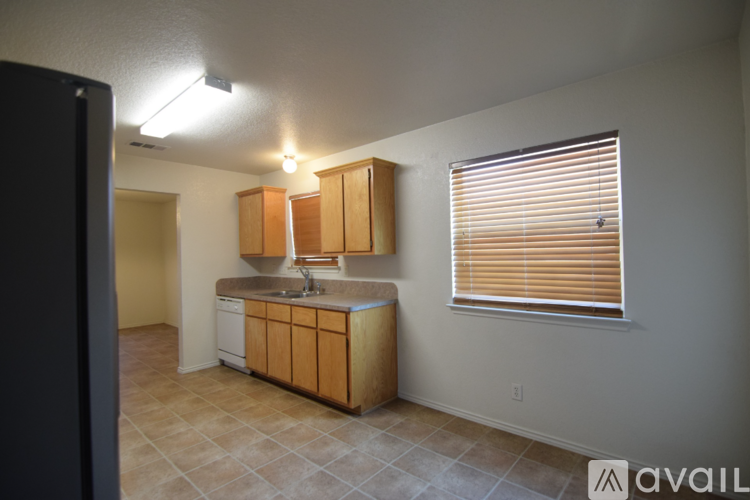 A kitchen with wooden cabinets and a window with blinds.