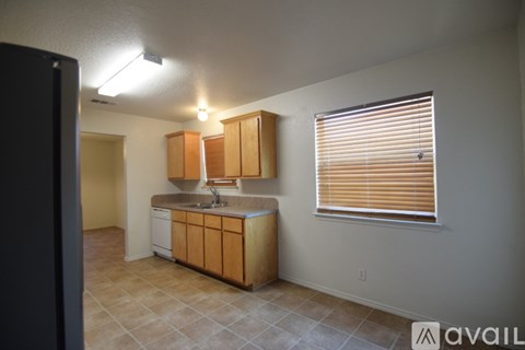 A kitchen with wooden cabinets and a window with blinds.