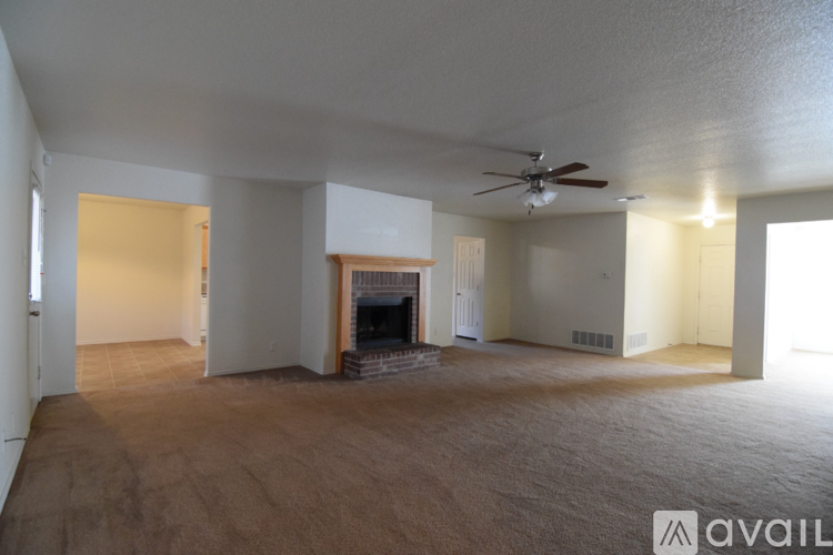 A living room with a fireplace and a ceiling fan.