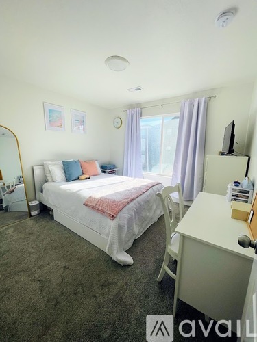 A bedroom with a bed, desk, and chair.