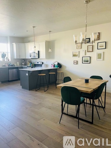 A kitchen with a table and chairs in the foreground and a chandelier hanging from the ceiling.