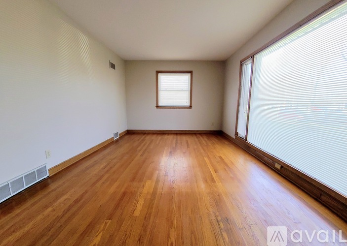 A room with wooden flooring and a window with blinds.