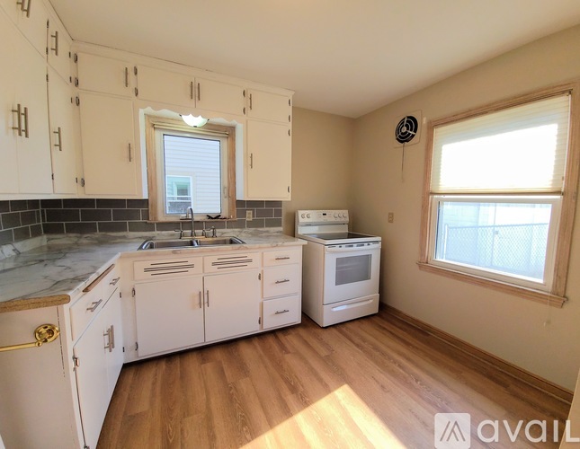 A kitchen with white cabinets and a marble countertop.