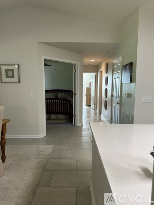 A hallway with a white counter on the right and a doorway leading to a bedroom.