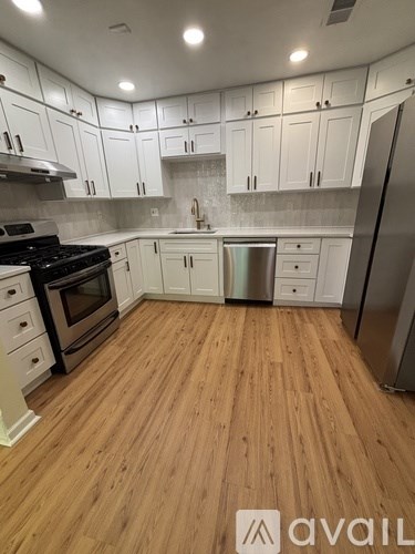 A kitchen with white cabinets and wooden floors.