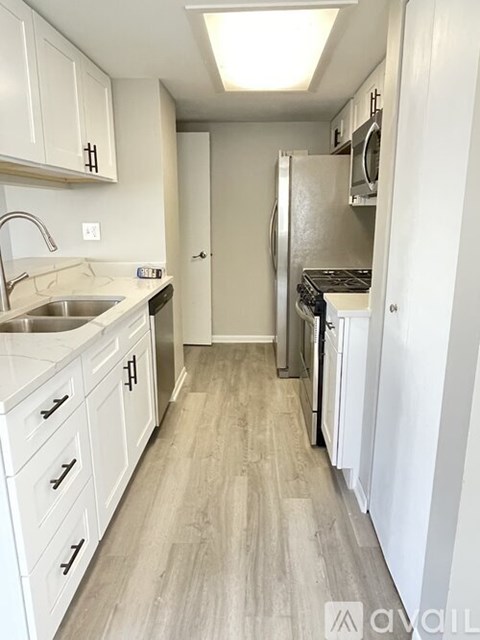 A kitchen with white cabinets and a white refrigerator.