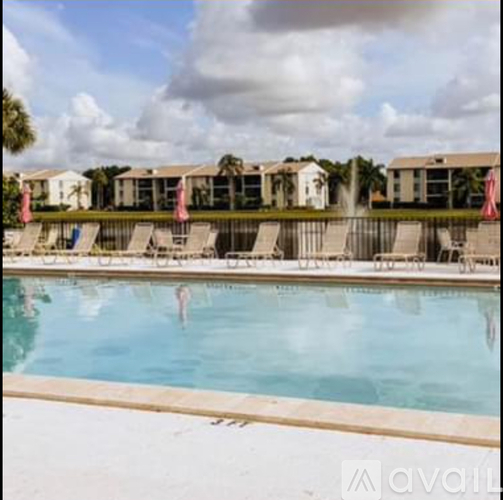 A swimming pool with a person swimming in it and lounge chairs around it.