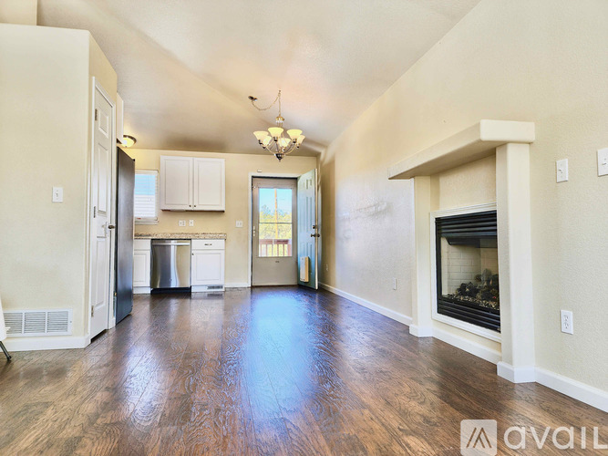 A spacious living room with wood flooring and a fireplace.