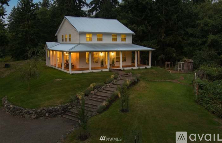 A house with a white exterior and a porch with lights on it.