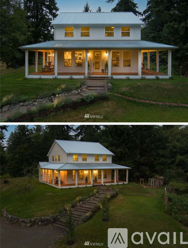 A white house with a porch and lights on.