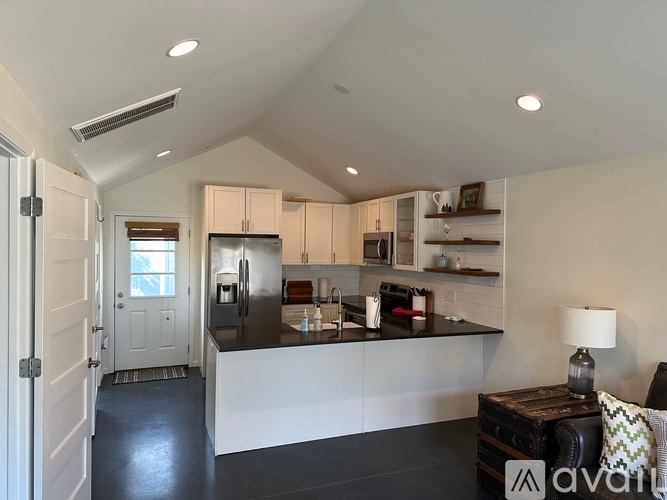 A kitchen with white cabinets and black countertops.