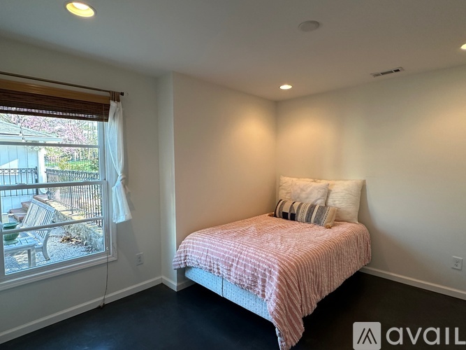A bedroom with a bed and a window overlooking a patio.
