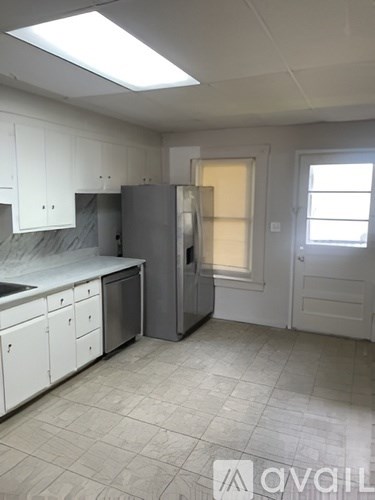 A kitchen with white cabinets and a grey fridge.