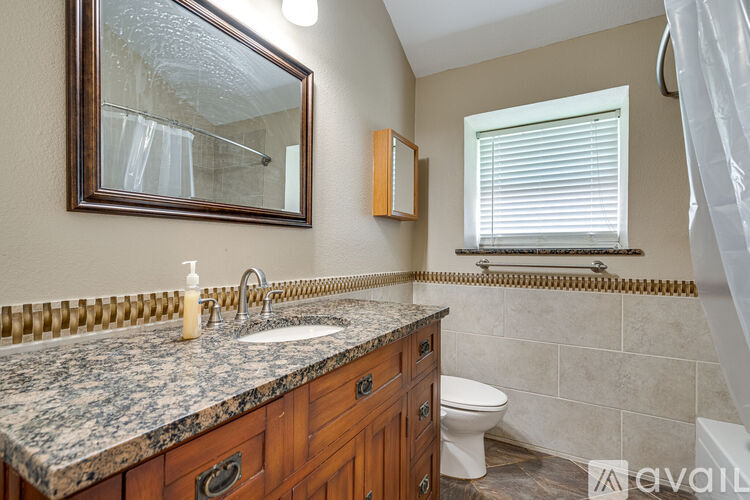 A bathroom with a granite countertop and a large mirror.