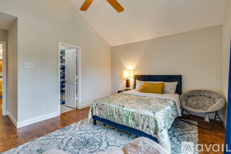 A bedroom with a bed, a chair, and a ceiling fan.