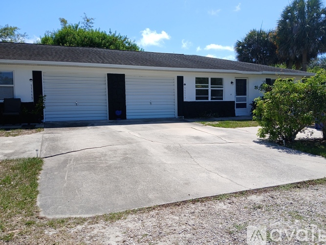 A white building with a grey roof and a black door.