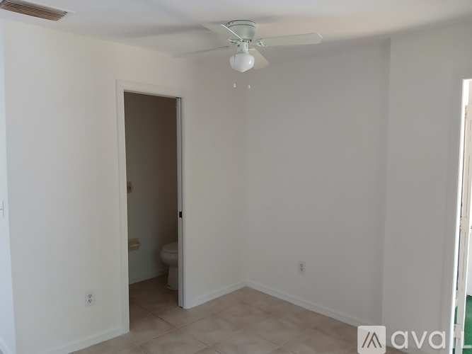 A room with a ceiling fan and a doorway leading to a bathroom.