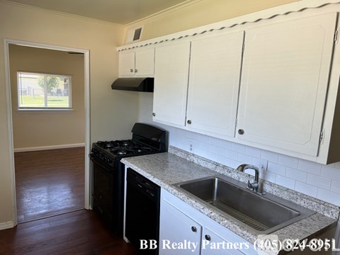 A kitchen with white cabinets and a black stove top oven.