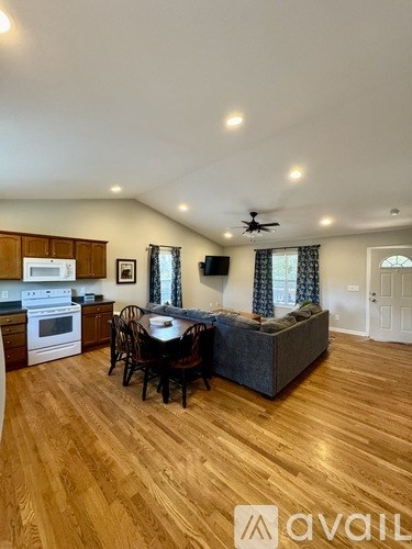 A kitchen with wooden floors and a dining area with a table and chairs.
