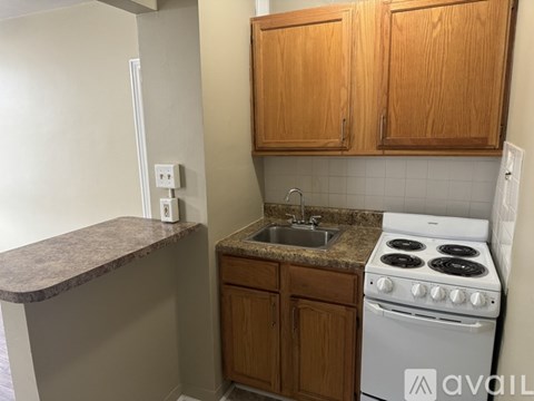 A kitchen with a white stove, wooden cabinets, and a granite countertop.