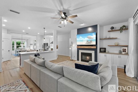 A modern living room with a grey sofa and a flat screen TV mounted above a fireplace.