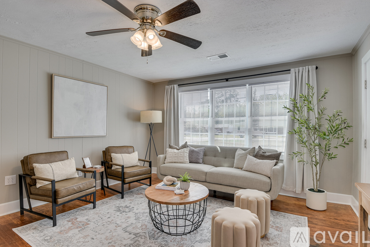 A living room with a ceiling fan, two chairs, a couch, a coffee table, and a plant.