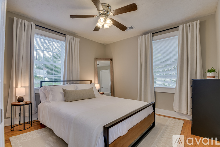 A bedroom with a large bed, a ceiling fan, and a window with curtains.