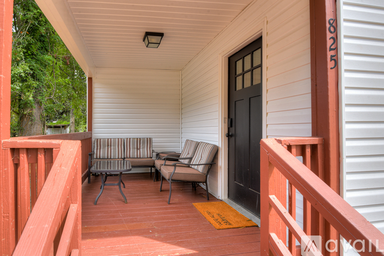A porch with a black door and a yellow mat.