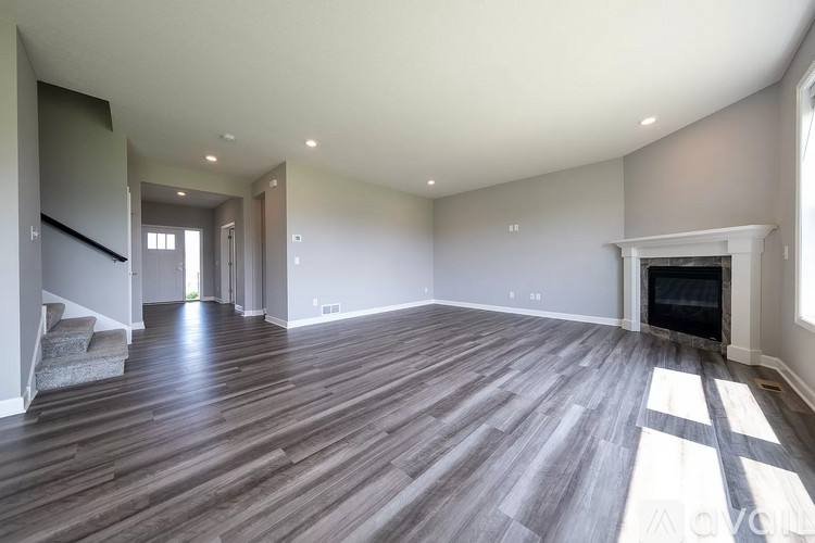 A spacious living room with wood flooring and a fireplace.