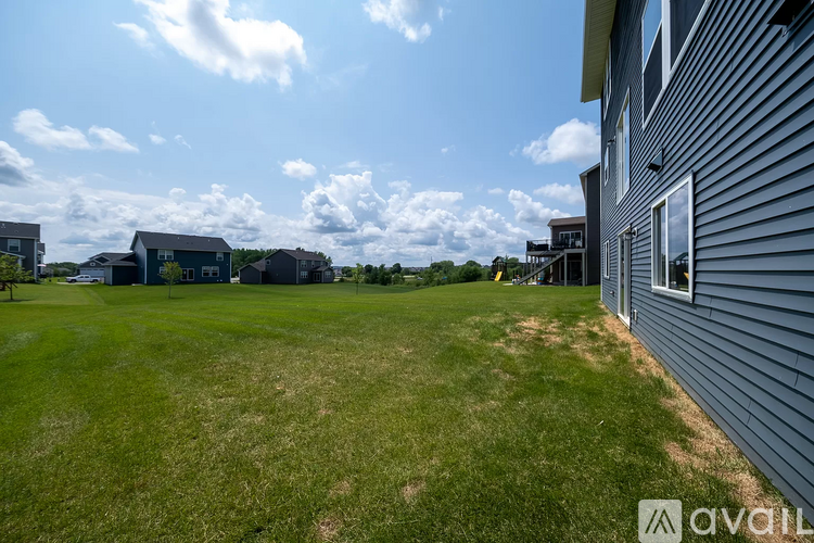 A grassy field with a building on the right side and a cloudy sky above.