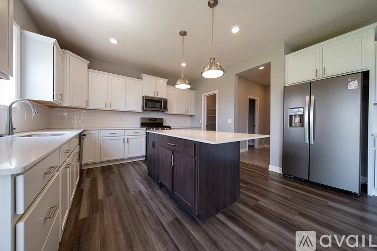 A kitchen with white cabinets and a dark island.