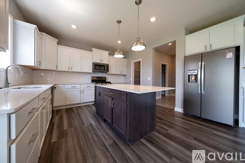 A kitchen with white cabinets and a dark island.