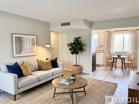 A living room with a grey couch, a wooden coffee table, and a dining table with chairs.