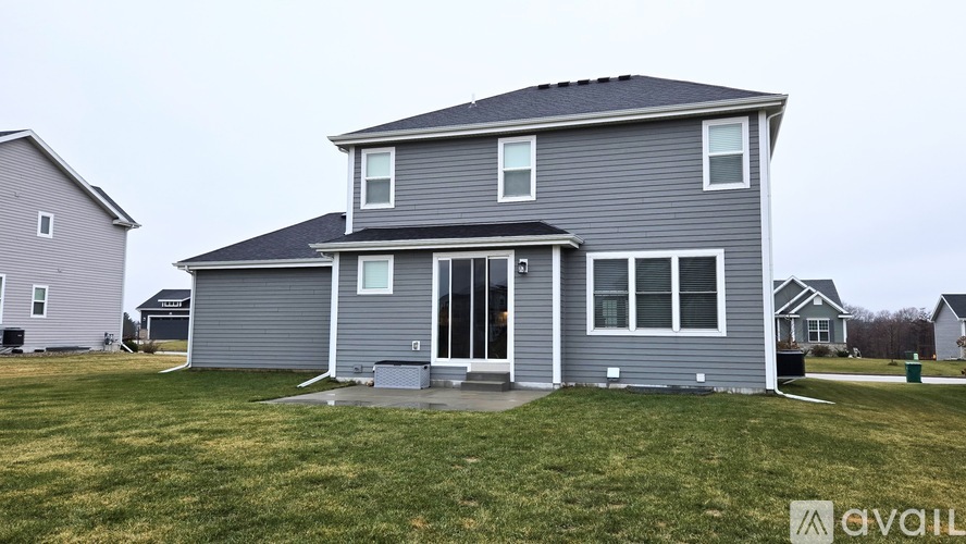 A two-story house with a grey exterior and a large front yard.