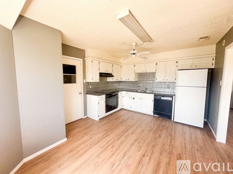A kitchen with white cabinets and a wooden floor.