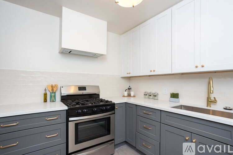 A kitchen with a stove, sink, and cabinets.