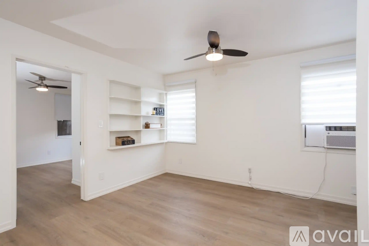 A spacious room with a ceiling fan and a window with blinds.