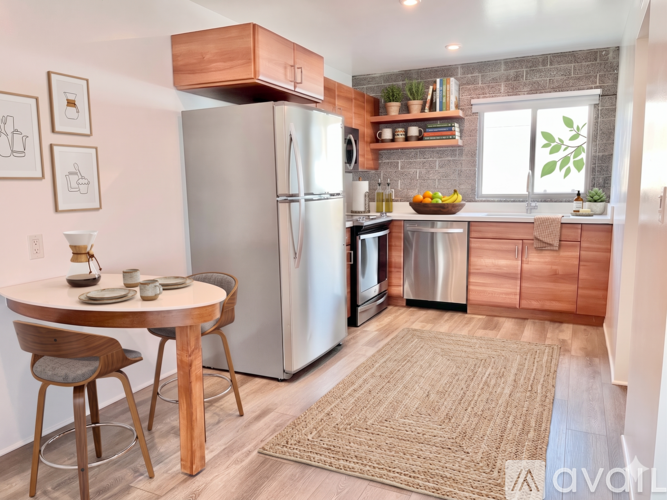 A kitchen with a refrigerator, dining table and chairs.