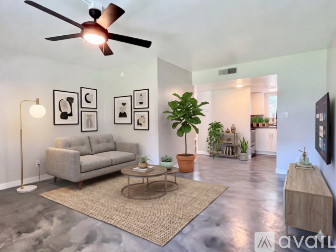 A living room with a grey couch, a coffee table, and a ceiling fan.