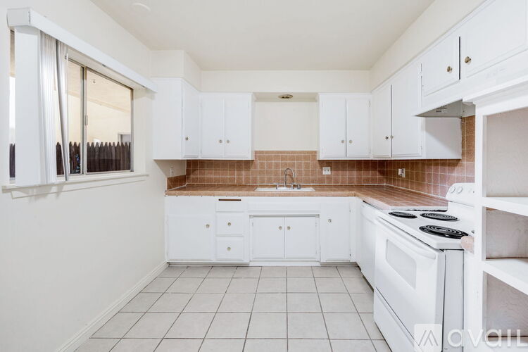 A kitchen with white cabinets and a tiled floor.