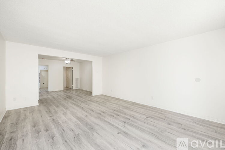 A spacious room with wooden flooring and white walls.