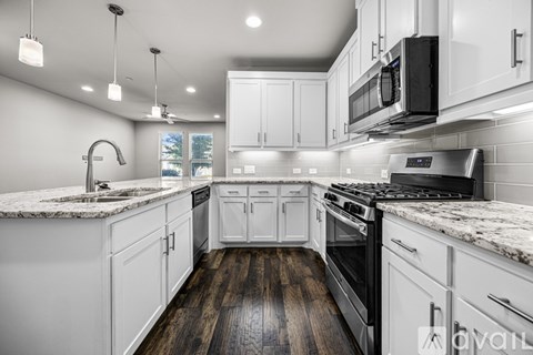 A modern kitchen with white cabinets and a dark countertop.