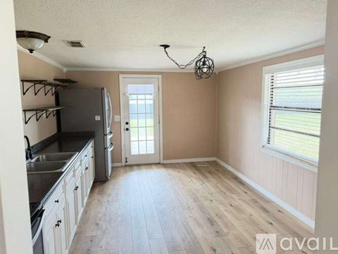 A kitchen with a refrigerator, sink, and wooden floors.