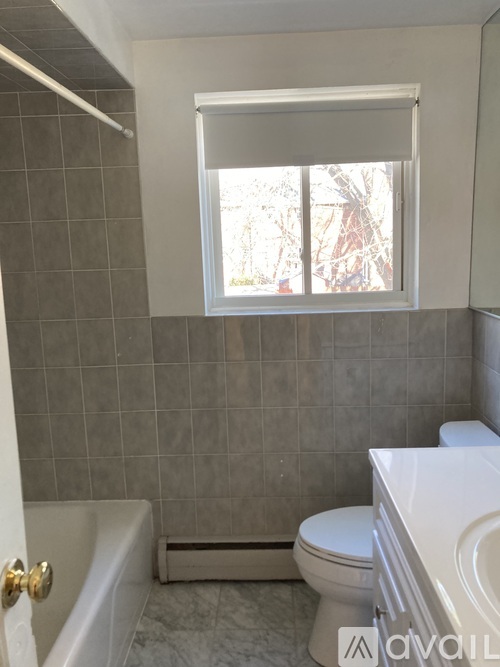 A bathroom with a tub, toilet and window.
