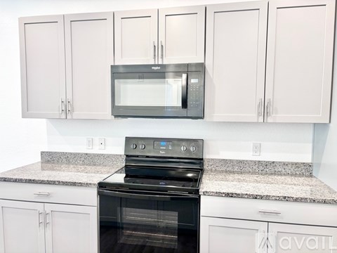 A kitchen with a black oven and white cabinets.