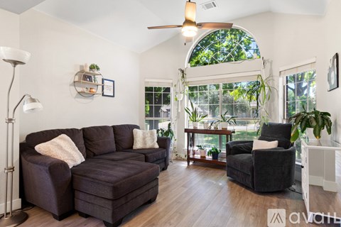 A living room with a brown couch and a black chair.
