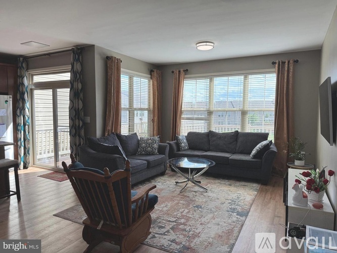A living room with a black couch, a wooden chair, and a coffee table.