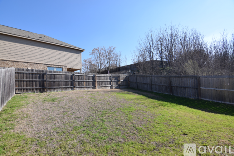 A backyard with a wooden fence and a house in the background.