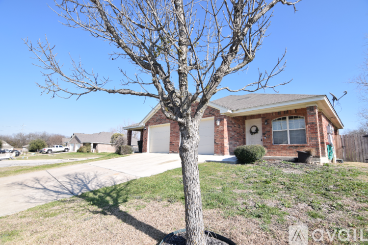 A bare tree stands in front of a brick house.