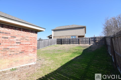 A backyard with a fence and a building in the background.